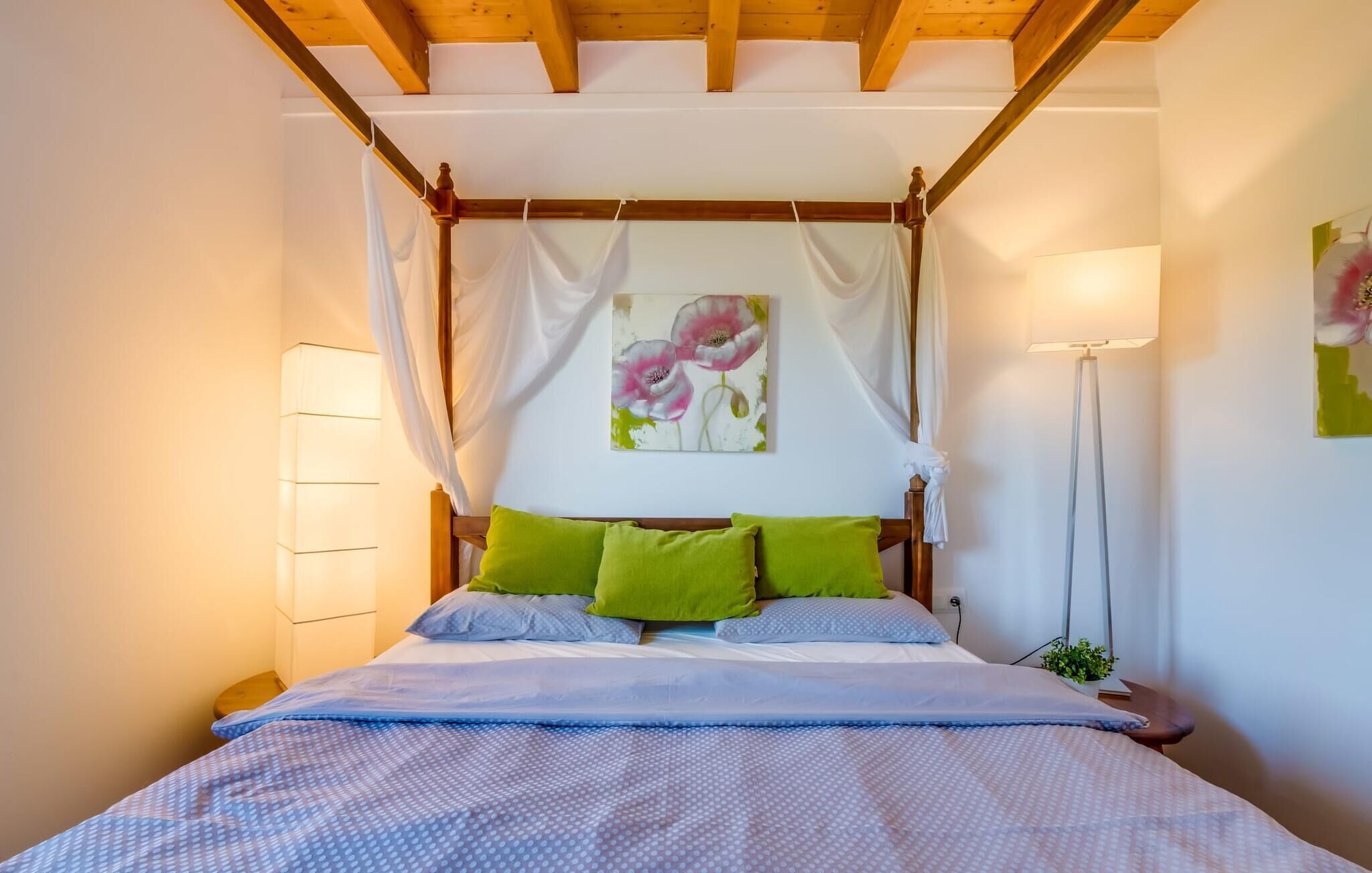 Une chambre à coucher avec un lit à baldaquin, des oreillers verts et un dais.