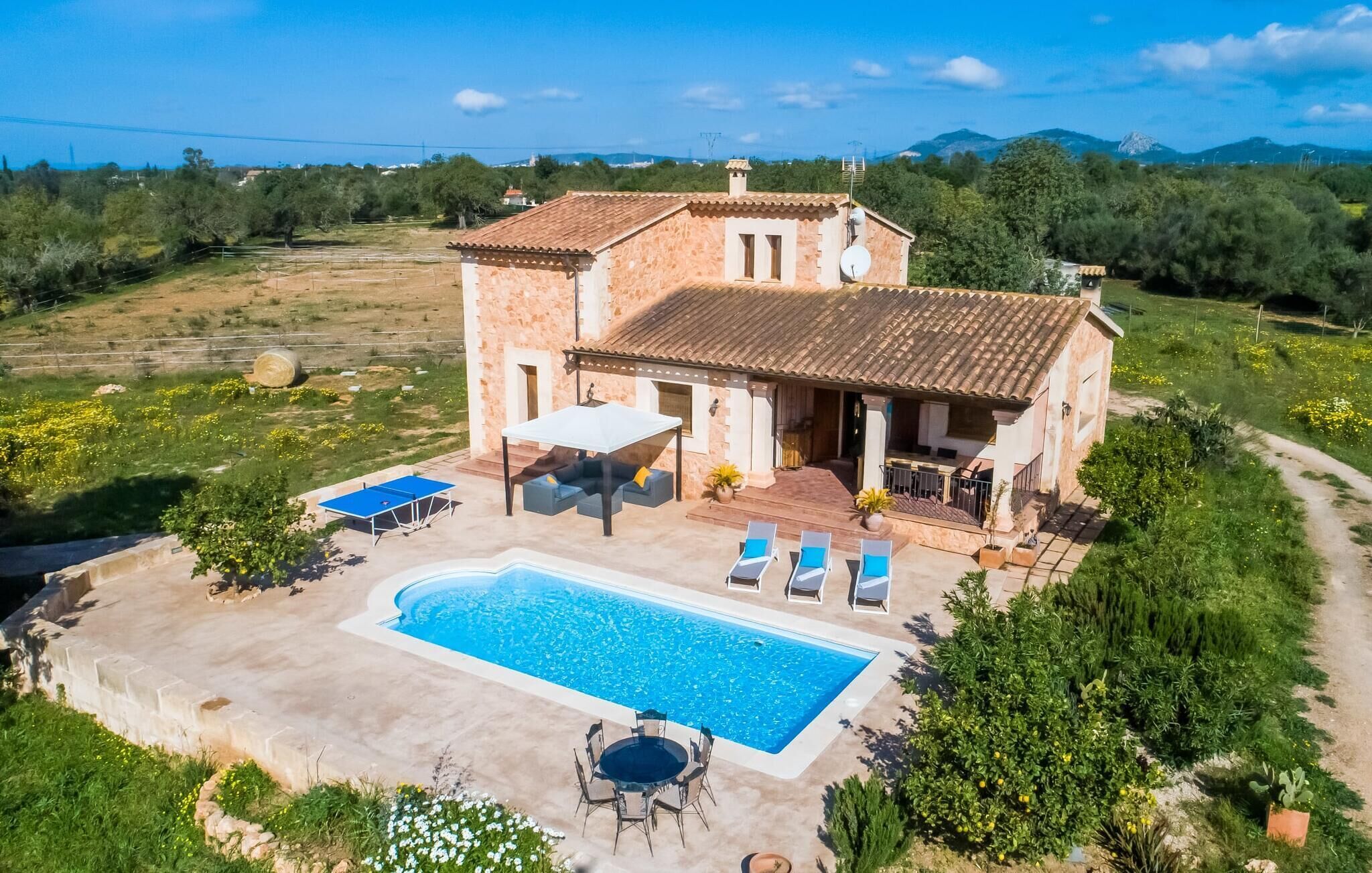 Une maison en pierre à deux étages, dotée d’une piscine, d’un espace extérieur aménagé et d’un jardin.