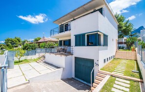 Ein modernes, zweistöckiges Haus mit Balkon, Garage und einem gepflegten Rasen.
