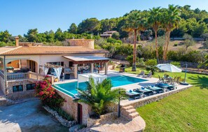 Eine Villa mit Swimmingpool, Sitzgelegenheiten im Freien und einem Garten.