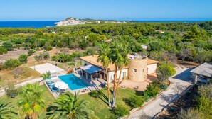 En villa med en swimmingpool, ett stentorn och utsikt över havet.