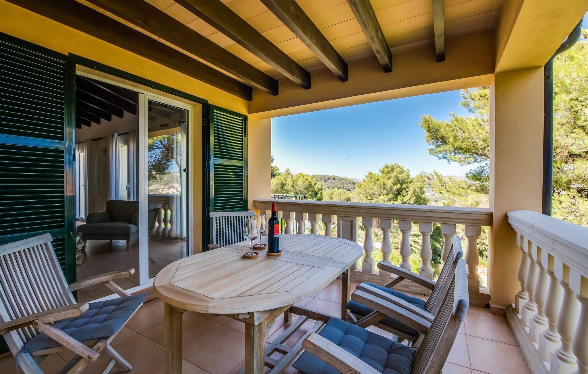 Un espace extérieur abrité, aménagé avec une table et des chaises, une bouteille de vin et offrant une vue sur le paysage environnant.