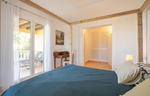 A bedroom with a bed, a desk, a chair, a lamp, and a sliding glass door leading to a balcony. - Beach front home in Capdepera (Capdepera)