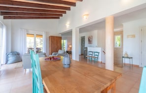 A spacious living area with a wooden dining table, teal chairs, and a large wooden cabinet. - Beach front home in Capdepera (Capdepera)