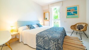 Une chambre à coucher avec un lit, une table de chevet, une lampe, une chaise et un tableau au mur.