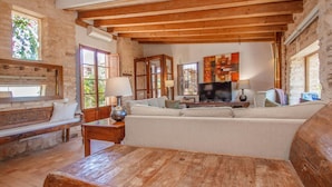 A rustic living room with exposed wooden beams, a sofa, a wooden coffee table, and a television. - Beautiful home in Es Trenc with private swimming pool, can be inside or outside (Es Trenc)