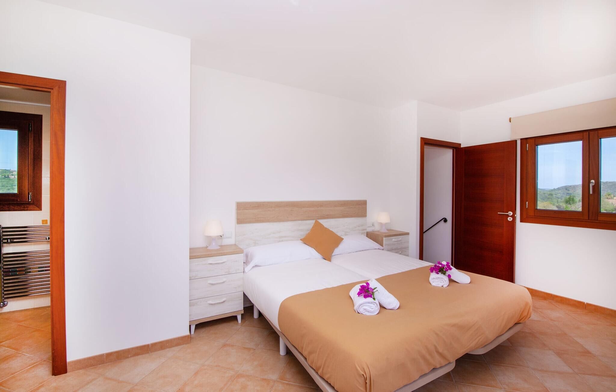 A hotel room with a bed, a nightstand, a wooden headboard, a window, and a door.