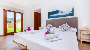 Ett hotellrum med en stor säng, två sängbord, en tavla och utsikt över en trädgård genom en skjutdörr.