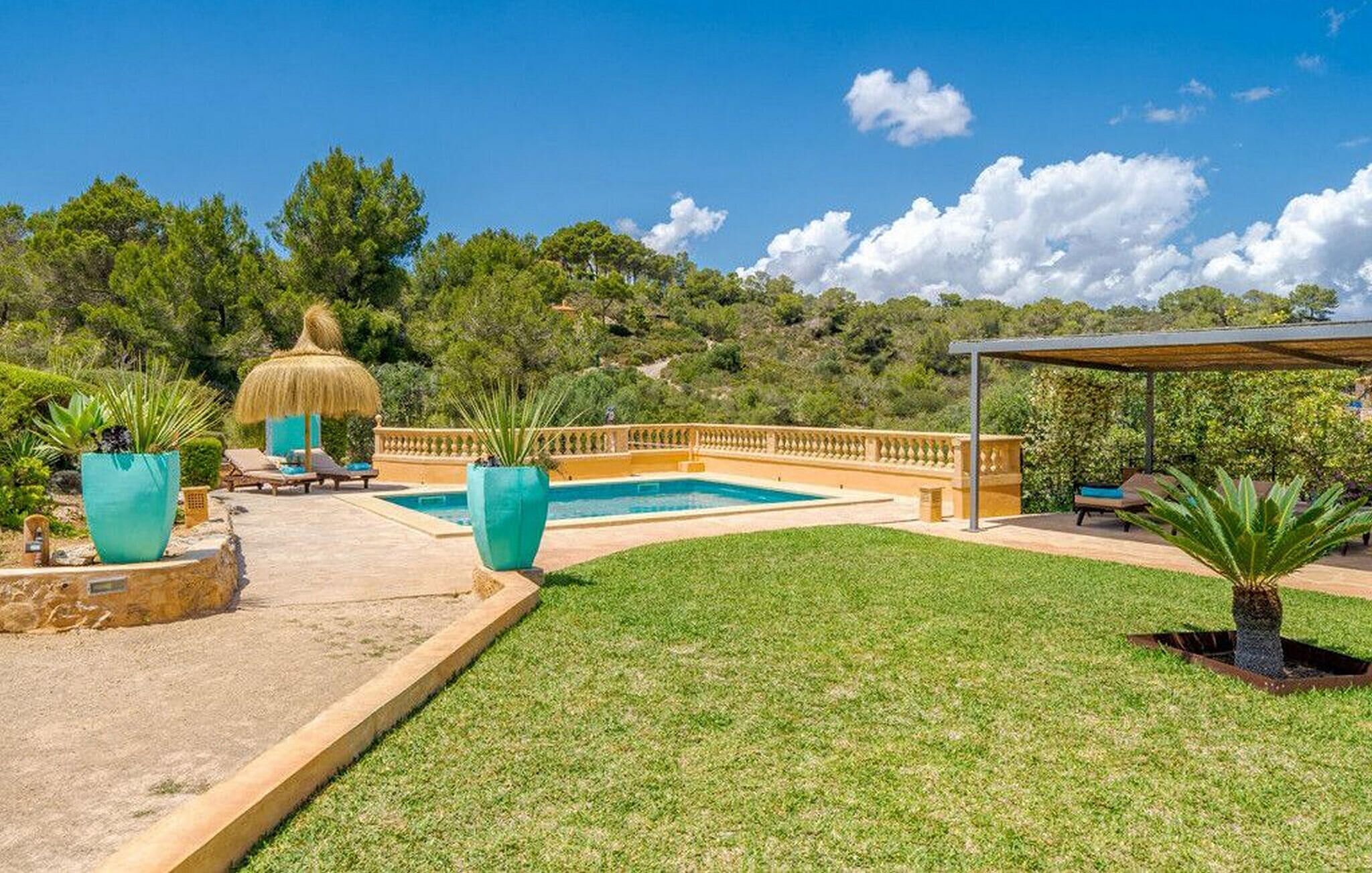 A pool area with a thatched umbrella, lounge chairs, and potted plants.