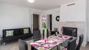 A modern living room with a glass-top dining table, black leather sofa, and a fireplace. - Gorgeous home in Canyamel with private swimming pool, can be inside or outside (Canyamel)