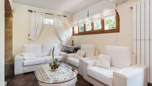 A living room with white furniture, a glass coffee table, and a window with curtains. - Awesome home in Cala Ratjada (Cala Ratjada)