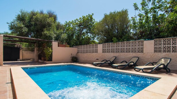 A rectangular swimming pool with clear blue water, surrounded by a tiled deck. There are lounge chairs along the poolside, and a decorative wall with a geometric pattern. - Awesome home in Cala Ratjada (Cala Ratjada)