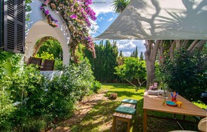 A garden with a wooden table, benches, and a white umbrella. - Beautiful home in Cala Millor (Cala Millor)