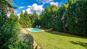 A backyard with a swimming pool, surrounded by lush greenery and trees. - Beautiful home in Cala Millor (Cala Millor)