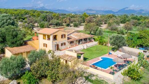 Une villa de style méditerranéen dotée d’une piscine, entourée d’une végétation luxuriante et avec des montagnes en toile de fond.