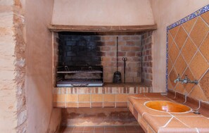 Ein kleines Badezimmer mit gefliestem Boden, einem Waschbecken mit dekorativer Schale und einer Ziegelwand mit eingelassener Grill.