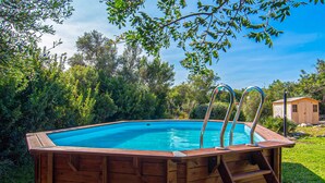 A wooden hot tub with metal ladders, surrounded by lush greenery and a clear blue sky. - Cozy home in Capdepera with private swimming pool, can be inside or outside (Capdepera)