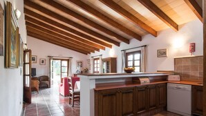 Una cocina con armarios de madera, encimera blanca y suelo de baldosas.