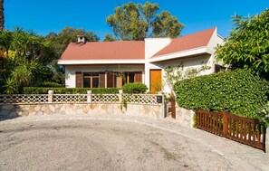 A two-story house with a gravel driveway and a wooden fence. - Beach front home in Canyamel (Canyamel)
