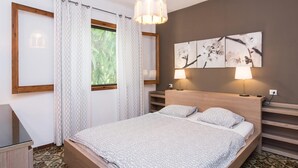 A bedroom with a bed, two bedside lamps, a window with curtains, and a wall-mounted artwork. - Beach front home in Canyamel (Canyamel)