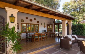 A covered patio with wooden furniture, a dining table, and a television. - Beach front home in Canyamel (Canyamel)