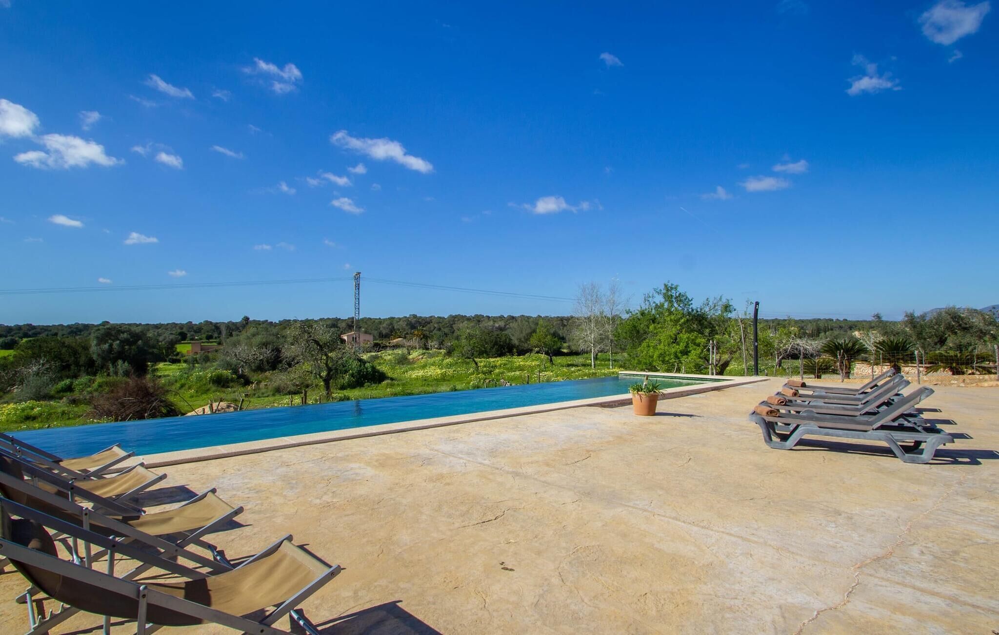 A poolside area with lounge chairs, a small pool, and a view of the surrounding landscape.