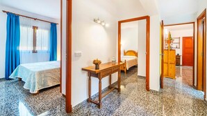 Une chambre d’hôtel avec un lit, une table de chevet ornée d’un vase, un miroir et une armoire en bois.