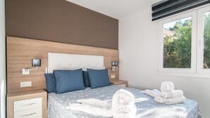 Une chambre à coucher avec un lit, des oreillers, des tables de chevet, une fenêtre et des serviettes.