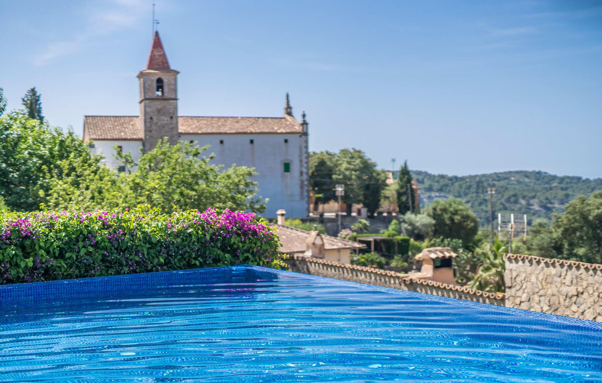 Une piscine offrant une vue dégagée sur une église et la végétation environnante.