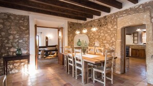 A dining area with a wooden table and chairs, stone walls, and exposed wooden beams. - Nice home in Pollenca with private swimming pool, can be inside or outside (Pollenca)