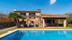 A stone house with a pool, outdoor seating, and a mountain backdrop. - Nice home in Pollenca with private swimming pool, can be inside or outside (Pollenca)
