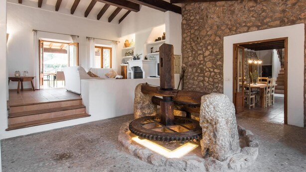 A rustic interior with exposed wooden beams, a stone wall, and a central water wheel feature. - Nice home in Pollenca with private swimming pool, can be inside or outside (Pollenca)