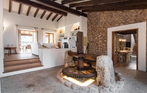 A rustic interior with exposed wooden beams, a stone wall, and a central water wheel feature. - Nice home in Pollenca with private swimming pool, can be inside or outside (Pollenca)