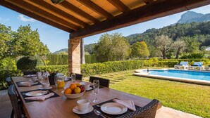 A dining table set outdoors with a view of a swimming pool and mountains in the background. - Nice home in Pollenca with private swimming pool, can be inside or outside (Pollenca)