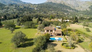 A stone villa with a swimming pool, surrounded by lush greenery and mountains in the background. - Nice home in Pollenca with private swimming pool, can be inside or outside (Pollenca)