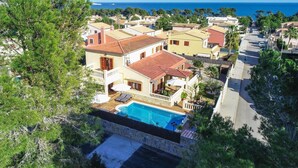 Una villa costera con piscina, varios balcones y vista al mar.