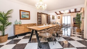 Un comedor con una mesa y sillas de madera, una araña y un suelo a cuadros.