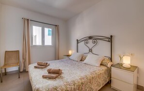 Ein ordentlich bezogenes Bett mit floralem Bettwäschemuster, einem Metall-Kopfteil und zwei Nachttischlampen.