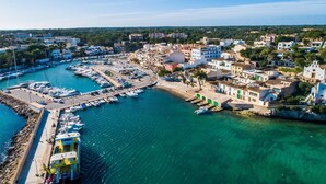 Una cittadina costiera con un porto turistico, edifici con balconi e un cielo azzurro limpido.