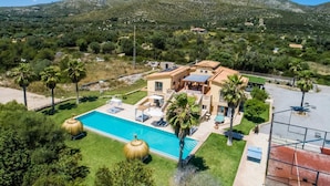 Une villa avec piscine, entourée de palmiers et dominée par un paysage montagneux.