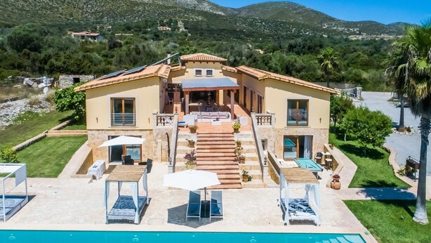 Une villa à deux étages dotée d’une piscine, d’un espace salon extérieur et offrant une vue sur les collines environnantes.