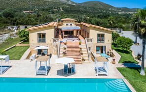 Een tweelaags villa met een zwembad, terras en uitzicht op de omliggende heuvels.