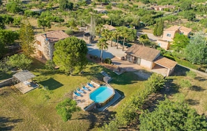 Ovenfra ses et boligområde med swimmingpool, flere huse og grøn bevoksning omkring.