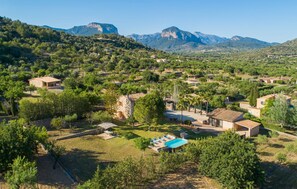 Zona rurale con case, una piscina e montagne sullo sfondo.