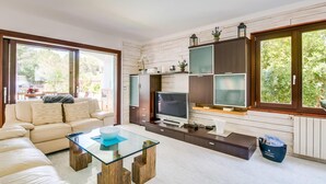 Un soggiorno moderno con un divano, un tavolino in vetro, una TV e scaffali a muro.