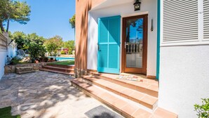 Una casa con un patio in pietra, una piscina e una porta con persiane blu.