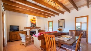 A cozy living room with a fireplace, a television, and a dining area with wooden furniture. - Beautiful home in Arta with private swimming pool, can be inside or outside (Arta)