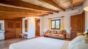 A bedroom with a large bed, wooden beams, a window with curtains, a small table, and a chair. - Beautiful home in Arta with private swimming pool, can be inside or outside (Arta)