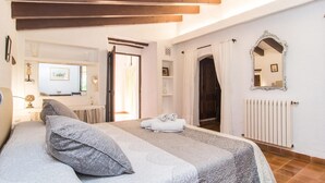Quarto com cama, espelho grande, radiador e porta que dá para outro cômodo.