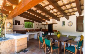 A rustic kitchen with a stone countertop, wooden chairs, and a dining table. - Beautiful home in Pollenca with private swimming pool, can be inside or outside (Pollenca)